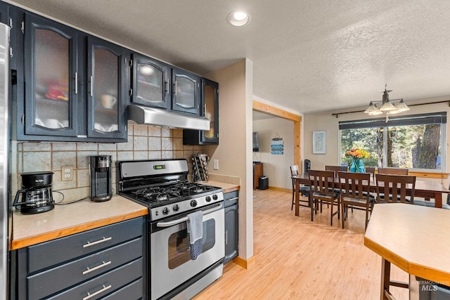 kitchen with stainless steel gas stove, tasteful backsplash, light wood-type flooring, and a textured ceiling