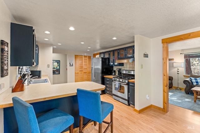 305 Gabi Ln, Mccall, ID 83638 - kitchen featuring a peninsula, appliances with stainless steel finishes, under cabinet range hood, a sink, and light wood finished floors