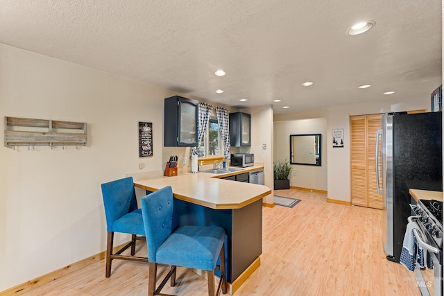 305 Gabi Ln, Mccall, ID 83638 - kitchen with light wood-style flooring, a kitchen bar, light countertops, stainless steel appliances, and baseboards