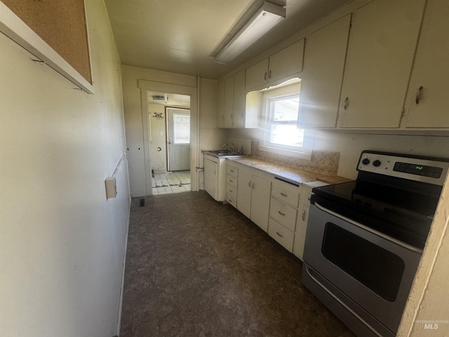 0203 22nd St, Lewiston, ID 83501 - kitchen featuring stainless steel range with electric stovetop, light countertops, a sink, white cabinets, and dark floors
