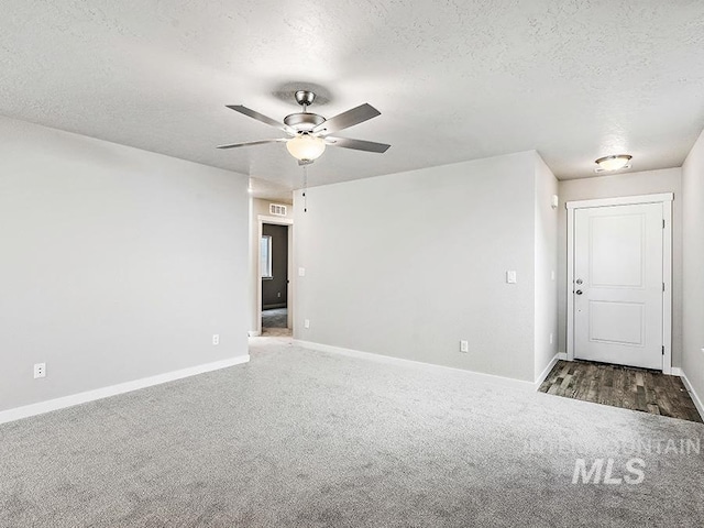 empty room featuring carpet, ceiling fan, and a textured ceiling