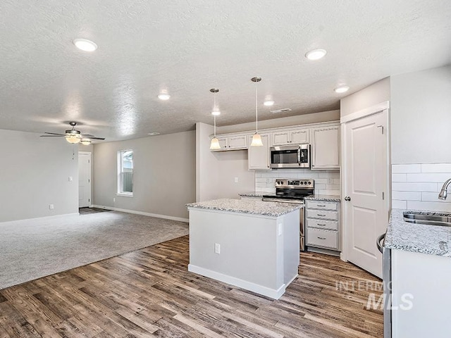 kitchen featuring white cabinetry, sink, stainless steel appliances, hardwood / wood-style floors, and pendant lighting