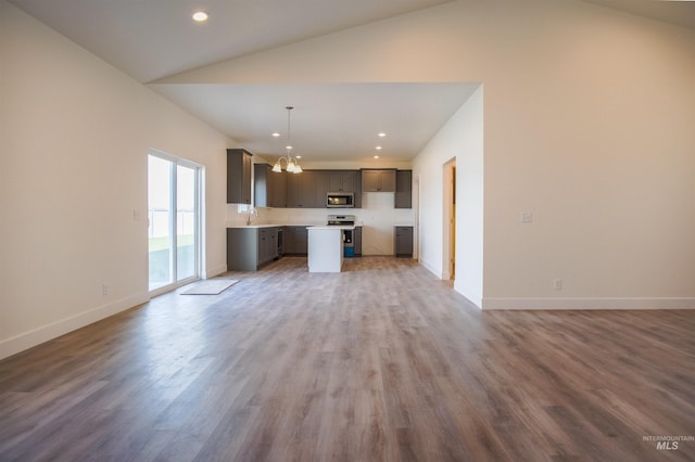 unfurnished living room featuring high vaulted ceiling, an inviting chandelier, sink, and light wood-type flooring