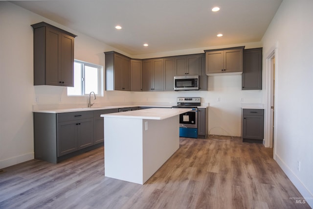 kitchen with hardwood / wood-style floors, appliances with stainless steel finishes, sink, a center island, and gray cabinets