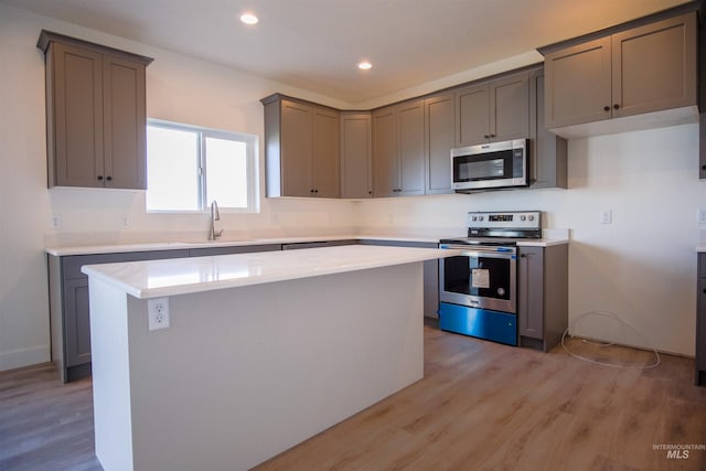 kitchen with a kitchen island, light hardwood / wood-style floors, appliances with stainless steel finishes, and gray cabinets
