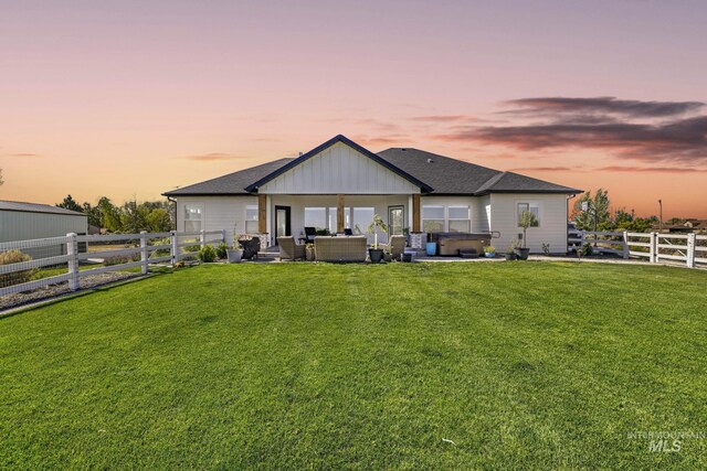 4064 China Ridge Dr, Kimberly, ID 83341 - back of house at dusk with a hot tub, an outdoor living space, a patio, and a shingled roof