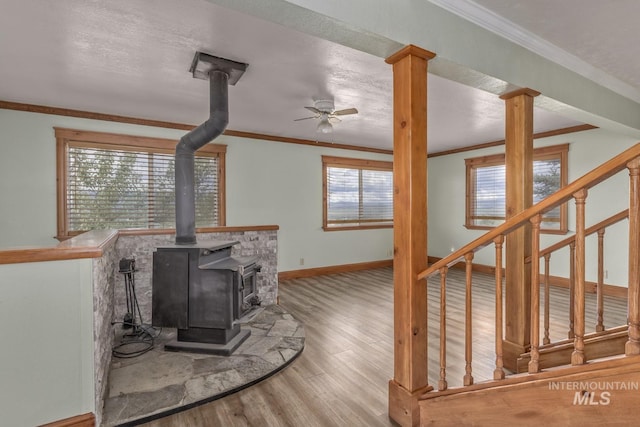 2445 Orchard Rd, Council, ID 83612 - unfurnished living room featuring a wood stove, a ceiling fan, crown molding, wood finished floors, and baseboards