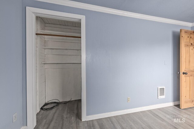 2445 Orchard Rd, Council, ID 83612 - unfurnished bedroom with wood finished floors, ornamental molding, a closet, baseboards, and a walk in closet