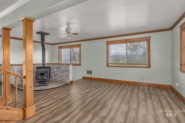2445 Orchard Rd, Council, ID 83612 - unfurnished living room with wood finished floors, ceiling fan, baseboards, a wood stove, and ornamental molding