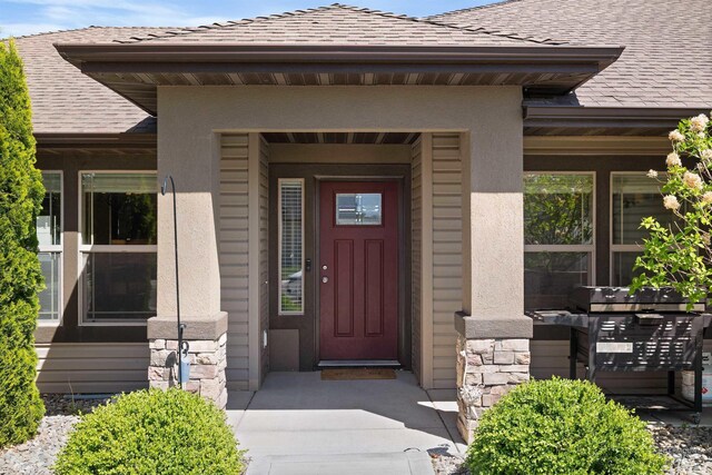 2448 Village St, Twin Falls, ID 83301 - view of exterior entry featuring stone siding, a shingled roof, and stucco siding
