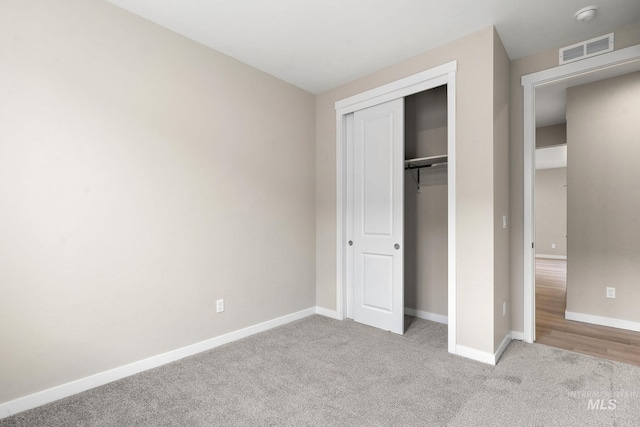 unfurnished bedroom with a closet, visible vents, light carpet, and baseboards