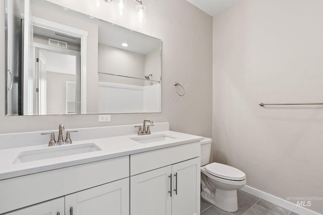 full bath featuring double vanity, toilet, a sink, and tile patterned floors