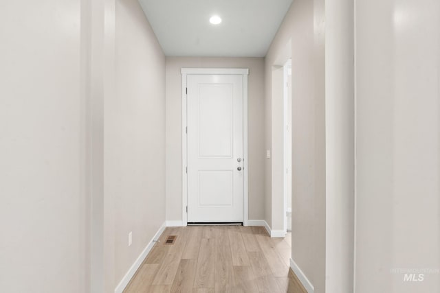 hallway with light wood-type flooring and baseboards