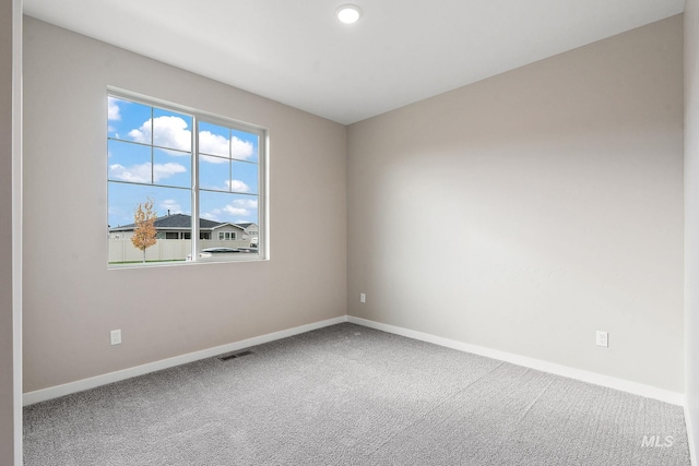 empty room with carpet, visible vents, and baseboards