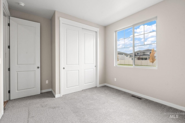 unfurnished bedroom with visible vents, baseboards, a closet, and light colored carpet