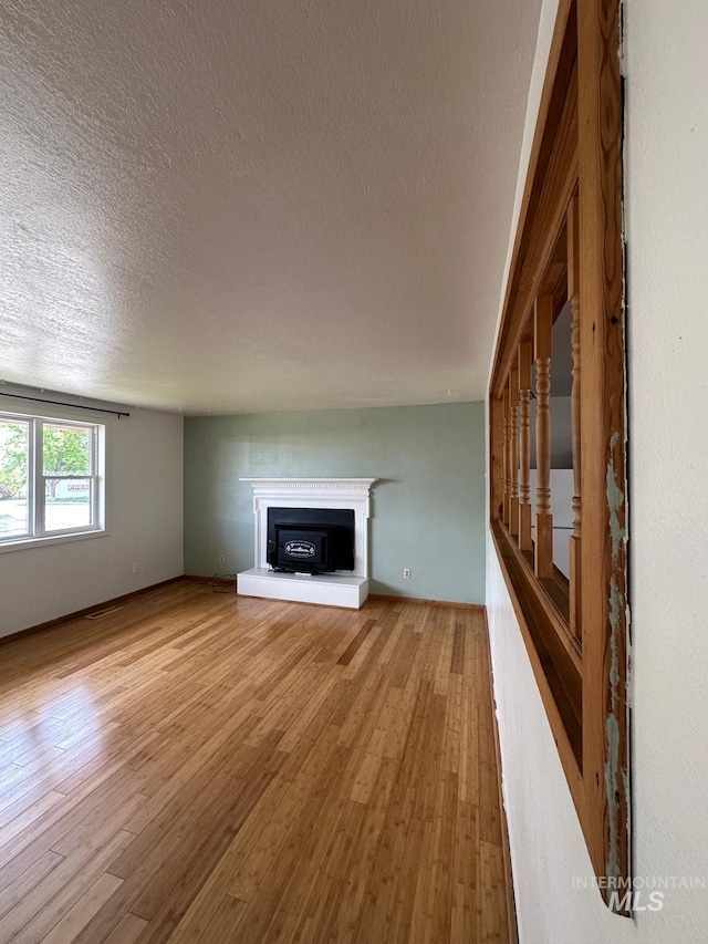 812 Thompson Ave, Nyssa, OR 97913 - unfurnished living room featuring light wood-style floors, a textured ceiling, a fireplace with raised hearth, and stairway