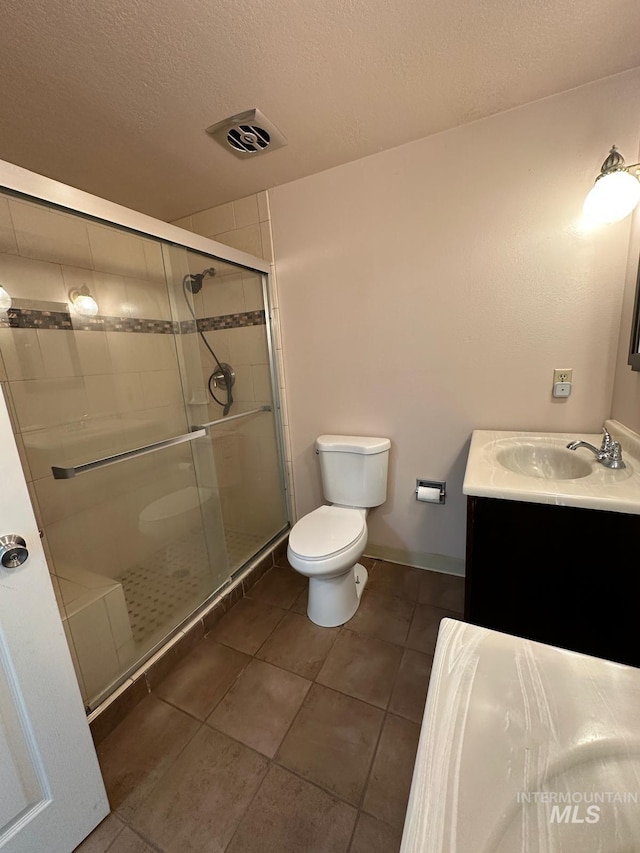 812 Thompson Ave, Nyssa, OR 97913 - bathroom with toilet, vanity, a stall shower, tile patterned floors, and a textured ceiling