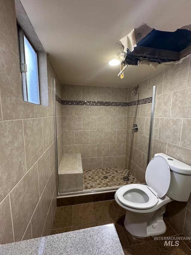 812 Thompson Ave, Nyssa, OR 97913 - bathroom featuring toilet, tiled shower, tile walls, and tile patterned flooring