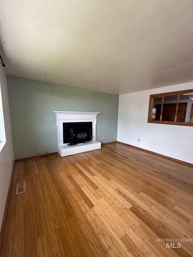 812 Thompson Ave, Nyssa, OR 97913 - unfurnished living room featuring hardwood / wood-style flooring, a textured ceiling, and a fireplace with raised hearth