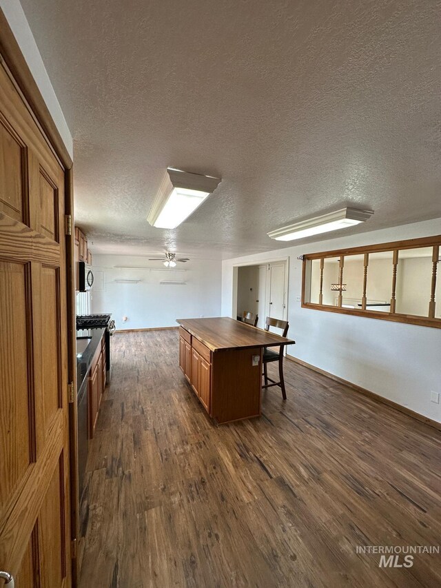 812 Thompson Ave, Nyssa, OR 97913 - kitchen with dark wood-type flooring, brown cabinetry, a textured ceiling, a kitchen island, and ceiling fan