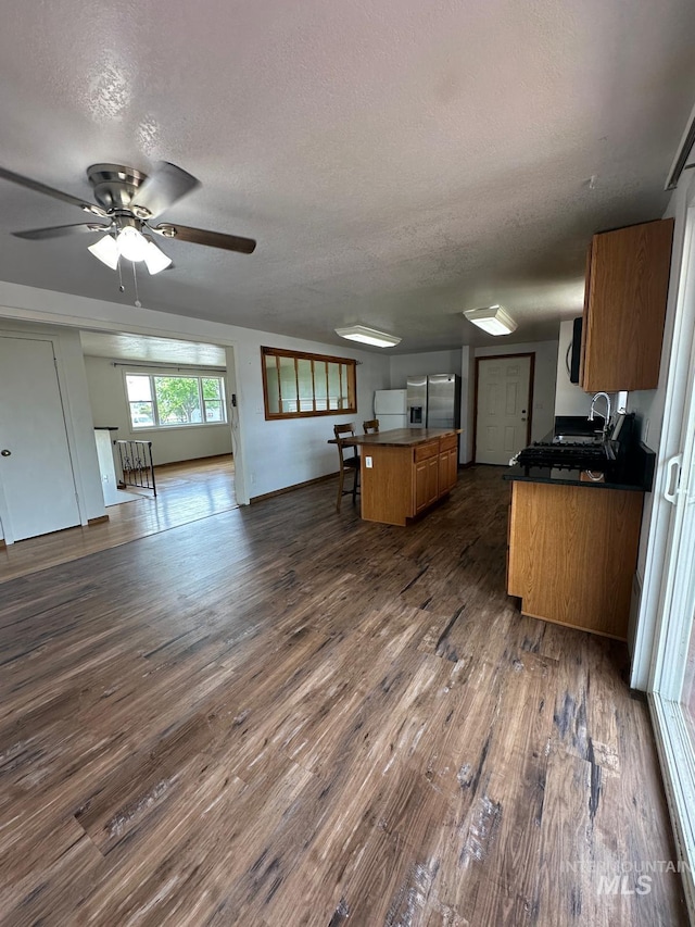 812 Thompson Ave, Nyssa, OR 97913 - kitchen with stainless steel fridge, a textured ceiling, open floor plan, dark wood-style flooring, and brown cabinetry