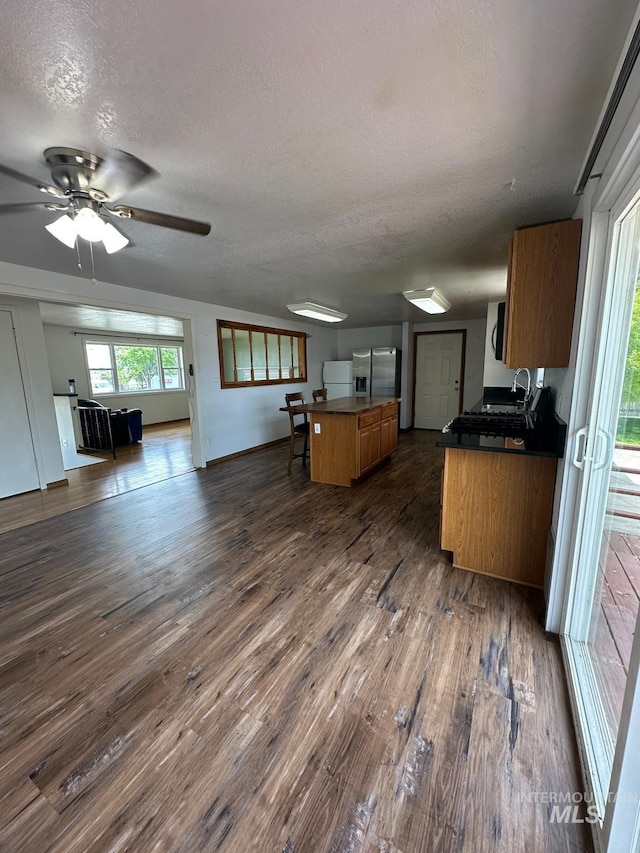 812 Thompson Ave, Nyssa, OR 97913 - kitchen featuring stainless steel refrigerator with ice dispenser, a sink, a textured ceiling, open floor plan, and dark wood finished floors