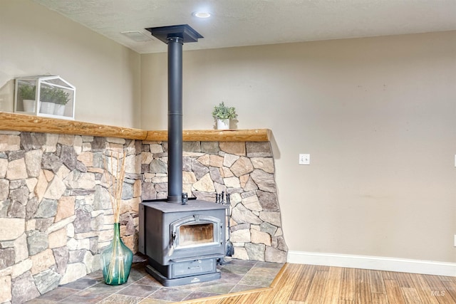 details with baseboards, a wood stove, and wood finished floors
