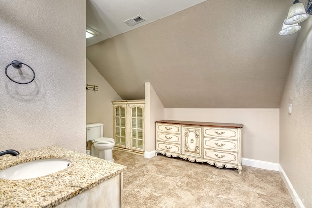 bathroom featuring lofted ceiling, visible vents, toilet, vanity, and baseboards