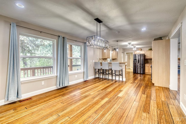 dining room featuring light wood-style flooring, baseboards, recessed lighting, and a textured ceiling