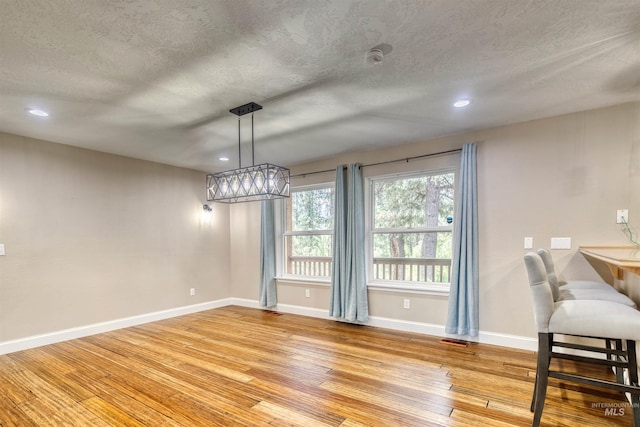 dining space featuring recessed lighting, baseboards, a textured ceiling, and light wood-style floors