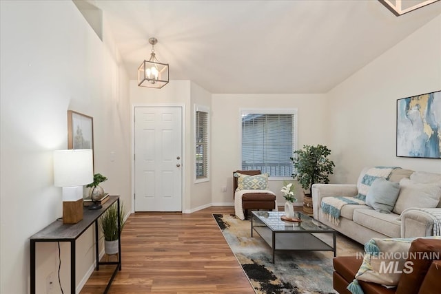 living room featuring wood finished floors, a chandelier, and baseboards