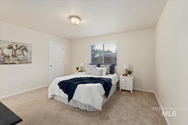 bedroom with carpet floors, baseboards, and a textured ceiling