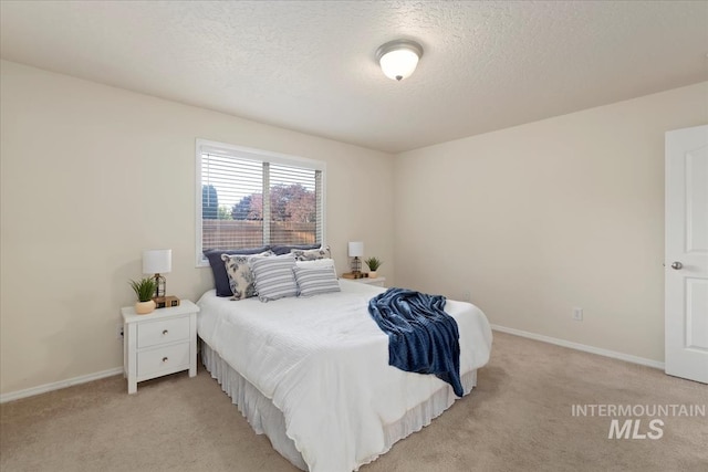 bedroom featuring light colored carpet, baseboards, and a textured ceiling
