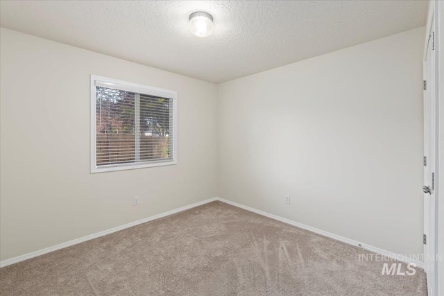 carpeted empty room with a textured ceiling and baseboards