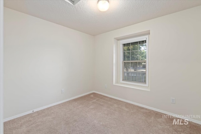 spare room featuring carpet flooring, a textured ceiling, and baseboards