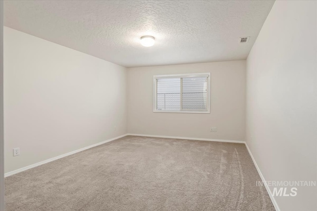 empty room with carpet floors, a textured ceiling, and baseboards