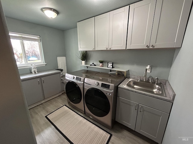 139 119th St, Orofino, ID 83544 - laundry area with light wood-type flooring, a sink, washing machine and clothes dryer, and cabinet space