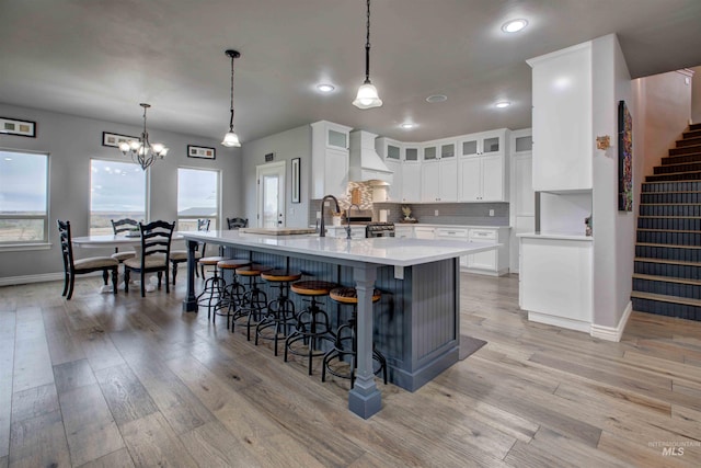 3330 E 4050 N, Twin Falls, ID 83301 - kitchen featuring custom range hood, light wood-type flooring, light countertops, and a kitchen bar