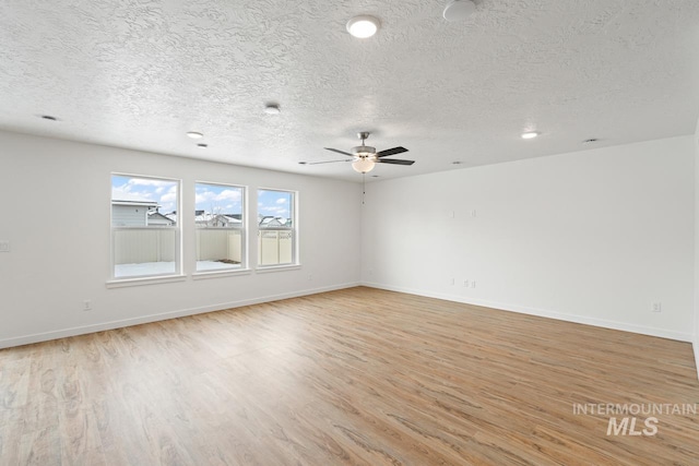 spare room featuring baseboards, a textured ceiling, ceiling fan, and light wood finished floors