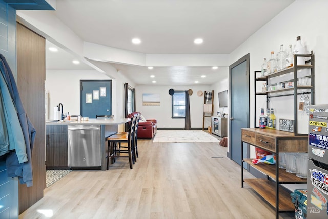 kitchen featuring kitchen peninsula, a kitchen breakfast bar, light hardwood / wood-style flooring, dishwasher, and sink