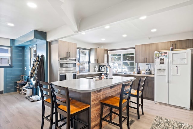 kitchen with sink, a breakfast bar, light hardwood / wood-style flooring, and white fridge with ice dispenser