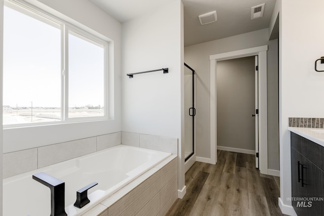 4372 N Magical Creek Ave, Meridian, ID 83646 - bathroom featuring a shower stall, a bath, wood finished floors, and visible vents