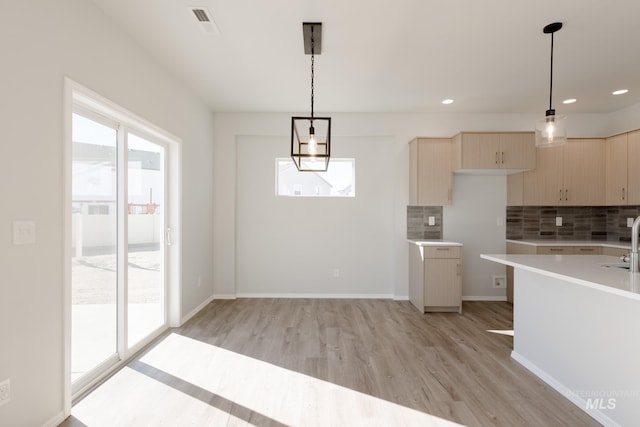 4372 N Magical Creek Ave, Meridian, ID 83646 - kitchen with light wood finished floors, pendant lighting, light countertops, and backsplash
