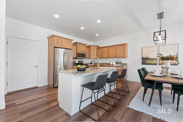 1447 N Pineview Ln, Boise, ID 83713 - kitchen featuring appliances with stainless steel finishes, a center island with sink, a kitchen bar, recessed lighting, and light stone counters