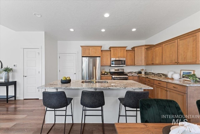1447 N Pineview Ln, Boise, ID 83713 - kitchen featuring stainless steel appliances, brown cabinets, a kitchen island with sink, a breakfast bar area, and recessed lighting