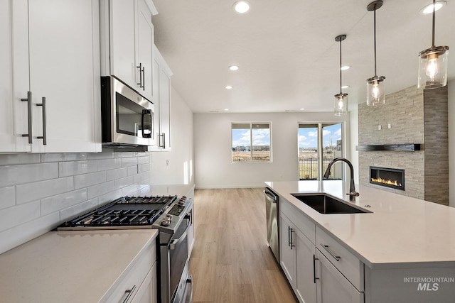 kitchen featuring a sink, backsplash, open floor plan, appliances with stainless steel finishes, and light countertops