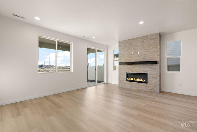 unfurnished living room with a fireplace, baseboards, visible vents, and light wood-type flooring