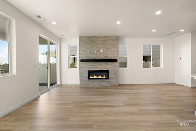 unfurnished living room with a wealth of natural light, light wood-type flooring, baseboards, and recessed lighting