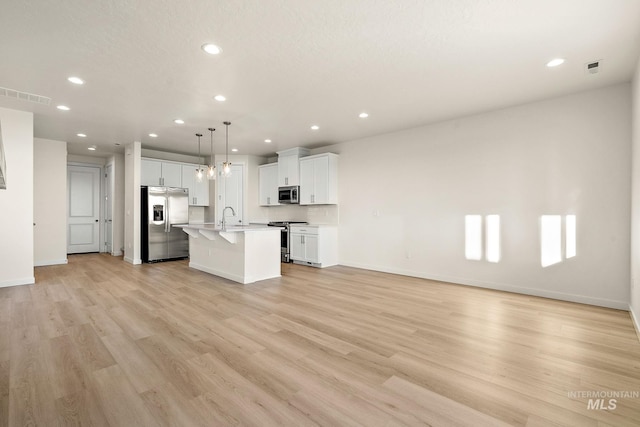 unfurnished living room with light wood finished floors, visible vents, baseboards, recessed lighting, and a sink