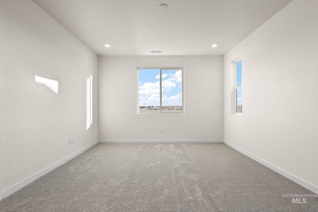 empty room featuring light carpet, visible vents, recessed lighting, and baseboards